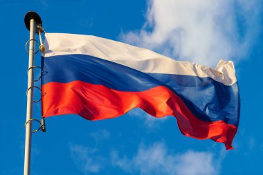Rusya 'nın dalgalanan bayrağı mavi gökyüzü arka planında dalgalanan bayrak direğinde