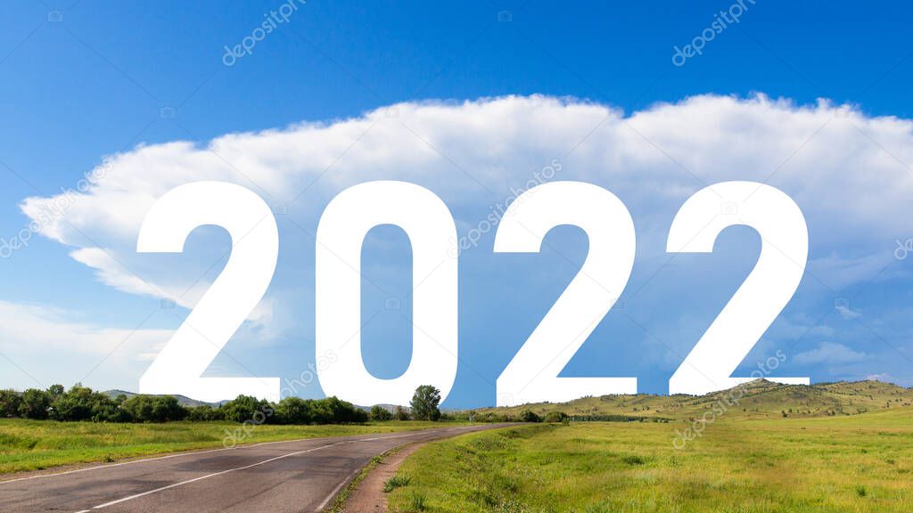 Inscription 2022 year among the sunny nature landscape. Empty asphalt road leading forward to happy new year 2022. Vision concept of global world travel without restriction