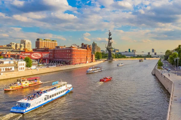 Moskova, Rusya - 20 Ağustos 2020: Moskva Nehri üzerinde Kızıl Ekim fabrikası manzaralı seyir ve Büyük Peter anıtı. Güneşli yaz akşamlarında nehirde bir sürü turist teknesi