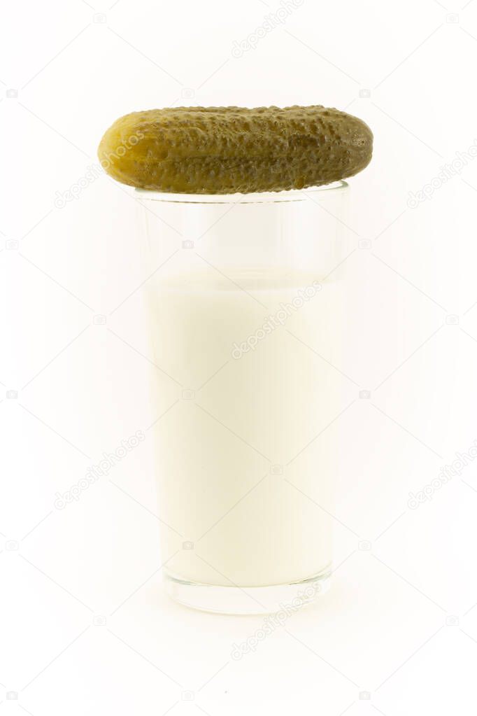 Pickled salty cucumber with a glass of milk isolated on a white background. Incompatible edible products. Concept of Indigestion or upset stomach and diarrhea