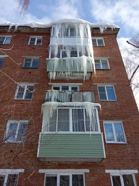 겨울에는 주거용 건물의 발코니에 고드름이 고드름이 떨어지는 사람들의 재산을 위태롭게 로열티 프리 스톡 이미지