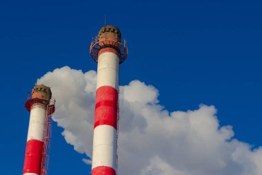 Mavi gökyüzüne karşı dumansız beyaz buharlı ve borusuz kırmızı ve beyaz kazan borusu. Kışın ısıtma mevsimi. Endüstriyel geçmiş. Yakıt yanmasından kaynaklanan hava kirliliği