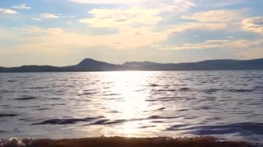 Su yüzeyinde güneş parlıyor. Gölde küçük dalgalar. Gölde yaz günü. Güneş ışığı su yüzeyine yansıyor.