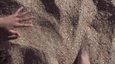 Erkek ayağının ve çocuğun üzerine kum koyduğu pov görüntüleri.