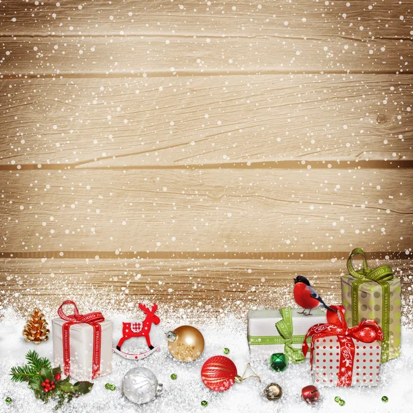 Christmas decorations and gifts in the snow on a wooden background — Stock Photo, Image