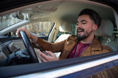 Trafikte araba sürerken mesaj atan yakışıklı genç adam.