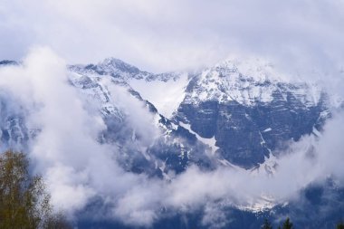 Bulutların oluşturduğu bir grup, karlı tepelerde sürünüyor.