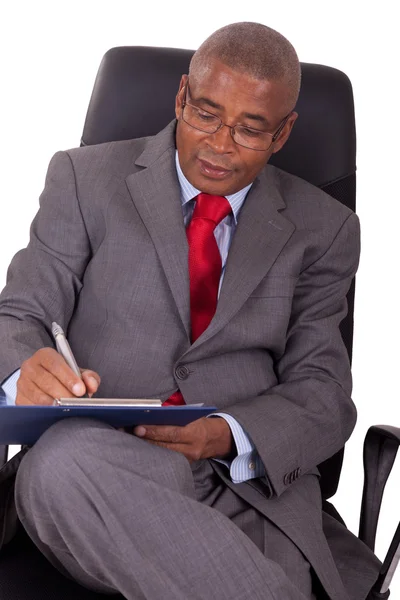 African businessman sitting in office chair isolated on white — Stock Photo, Image