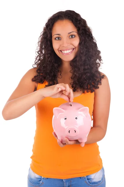 Young african american woman putting coin in piggy bank — Stock Photo, Image