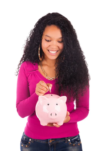 Young african american woman putting coin in piggy bank — Stock Photo, Image