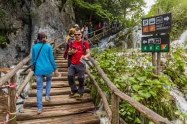 PLITVICE, CROATIA - MAY 24, 2019: Tourists visit Plitvice Lakes National Park, Croatia clipart