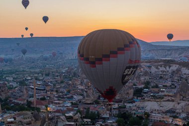 GOREME, TURKEY - 20 Temmuz 2019: Kapadokya, Türkiye 'deki Goreme köyü üzerindeki sıcak hava balonlarının sabah görüntüsü
