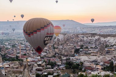 GOREME, TURKEY - 20 Temmuz 2019: Kapadokya, Türkiye 'deki Goreme köyü üzerindeki sıcak hava balonlarının sabah görüntüsü