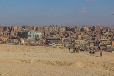 CAIRO, EGYPT - 28 HAZİRAN 2019: Kahire şehri, Mısır manzaralı Giza piramitleri yakınlarında at ve deveye binen turistler