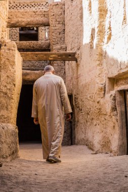 DAKHLA, EGYPT - 8 Şubat 2019: Mısır 'ın Dakhla vahasındaki El Kasr köyünde dar bir sokakta yürüyen yerel adam