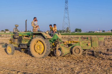 BAHAR, İRAN - 13 Temmuz 2019: İran 'ın Bahar kenti yakınlarındaki traktörlerinde çiftçi ailesi.