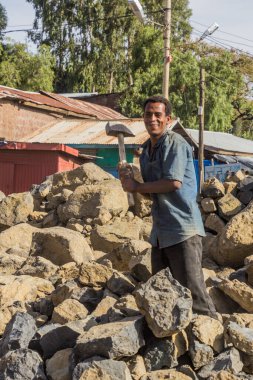 LALIBELA, ETHIOPIA - MARCH 29, 2019: Local worker breaking rocks on a road construction in Lalibela village, Ethiopia
