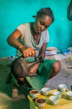LALIBELA, ETHIOPIA - MARCH 30, 2019: Girl serving a coffee in a settlement near Lalibela, Ethiopia