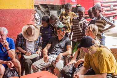 DANAKIL, ETHIOPIA - MARCH 25, 2019: Tourists and local children in a village in Afar region, Ethiopia.