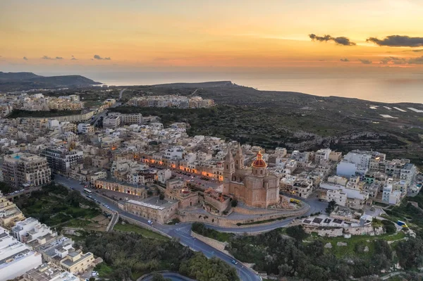 马耳他 北部地区 Mellieha 黄昏时沿海城镇的空中景观 中心是圣母玛利亚教区降生教堂 — 图库照片