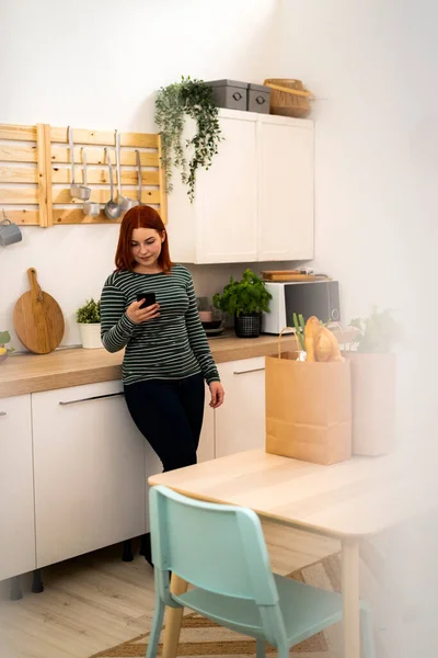 Rossa Donna Utilizzando Telefono Cellulare Mentre Piedi Cucina — Foto Stock