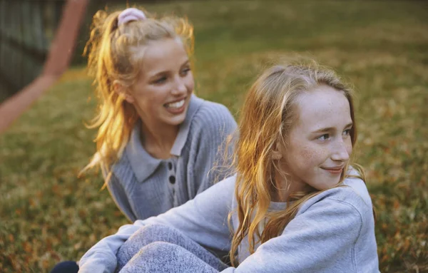 女孩们坐在公园的草地上 目瞪口呆 — 图库照片