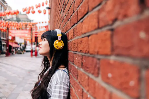 Vrouw Luisteren Muziek Door Middel Van Koptelefoon Door Baksteen Muur — Stockfoto