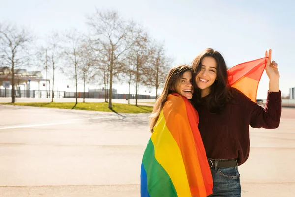阳光明媚的日子里 一对带着彩虹旗的年轻女同性恋夫妇 — 图库照片