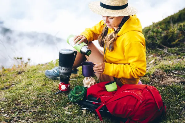 Woman Wearing Hat Pouring Tea Cup While Sitting Backpack Mountain — Stock Photo, Image