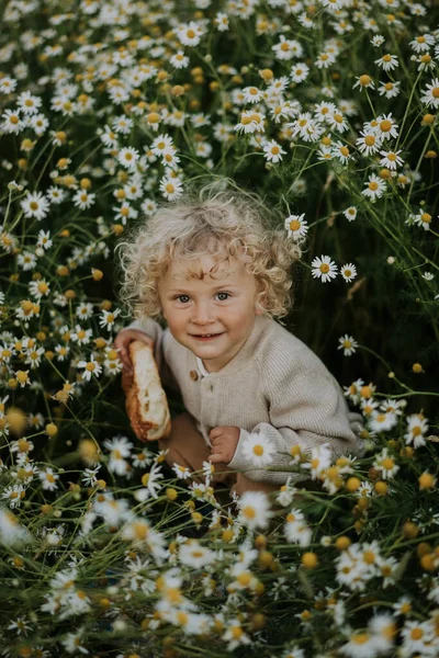Netter Junge Mit Donut Sitzt Inmitten Blühender Pflanzen Auf Dem — Stockfoto