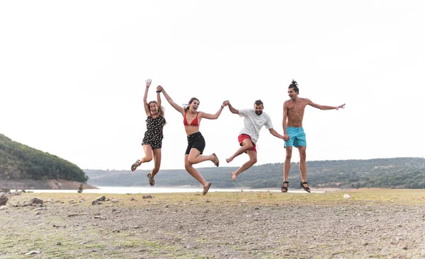 Беззаботные Мужчины Женщины Прыгающие Берегу Озера — стоковое фото