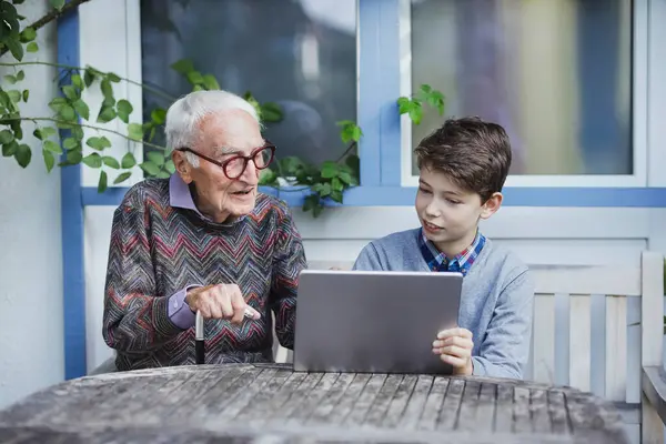 Senior Spricht Mit Enkel Der Mit Tablet Tisch Sitzt — Stockfoto