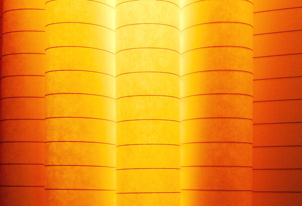 macro image of colorful curved sheets of paper shaped like a fan, on orange background