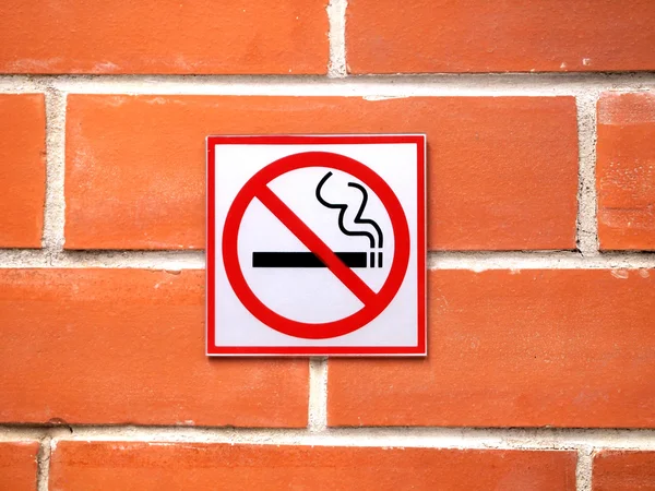 Σημάδι "κολλάει" σε έναν τοίχο από τούβλα προειδοποίηση ότι το κάπνισμα δεν επιτρέπεται στην περιοχή — Φωτογραφία Αρχείου