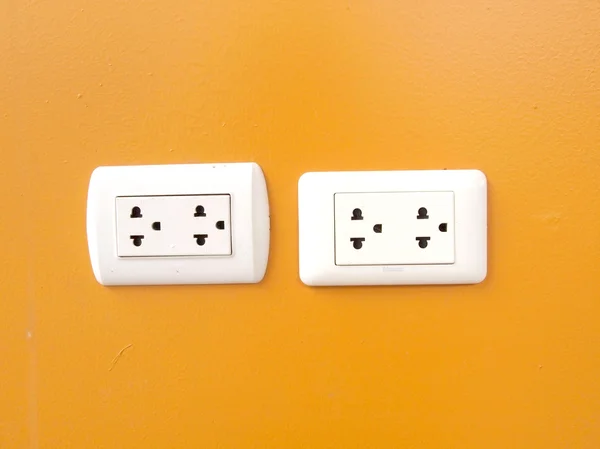 White electric outlet mounted on orange wall — Stock Photo, Image