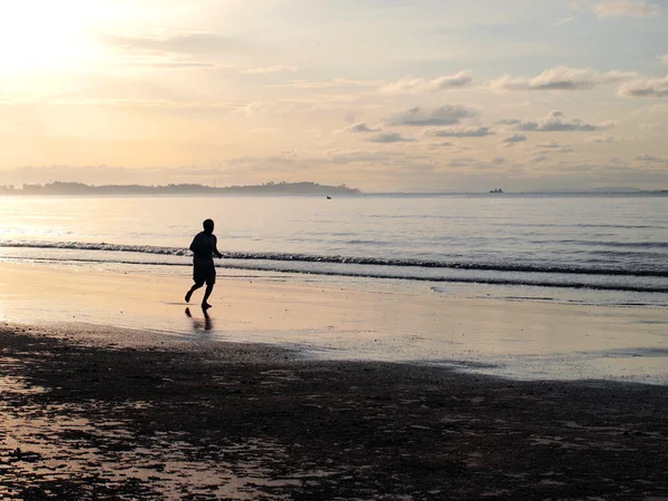Sylwetka człowieka działa na plaży podczas zachodu słońca — Zdjęcie stockowe