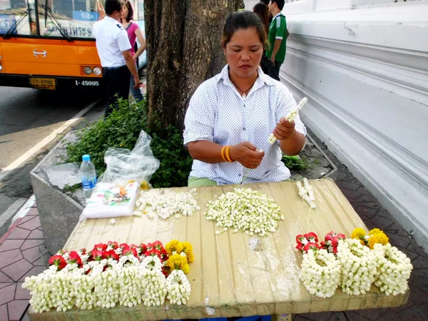 BANGKOK, THAILANDIA - 4 GENNAIO: Donna non identificata per fare ghirlande di fiori in stile tailandese da vendere per adorare a Wat Sutat il 4 gennaio 2012 a Bangkok, Thailandia . — Foto Stock