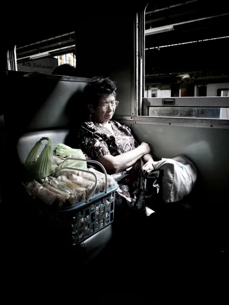 BANGKOK - JANUARY 10:  A old woman sleep in a bench of a train on January 10, 2012 in Bangkok, Thailand. — Stock Photo, Image