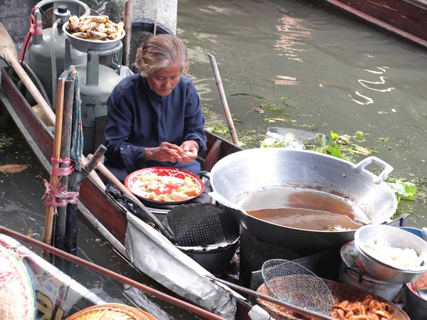 RATCHABURI, THAILAND-SEPTEMBER 2013: Local peoples sell fruits, food and products at Damnoen Saduak floating market, on September 7 2013 in Ratchaburi, Thailand. Dumnoen Saduak is a very popular tourist — стоковое фото