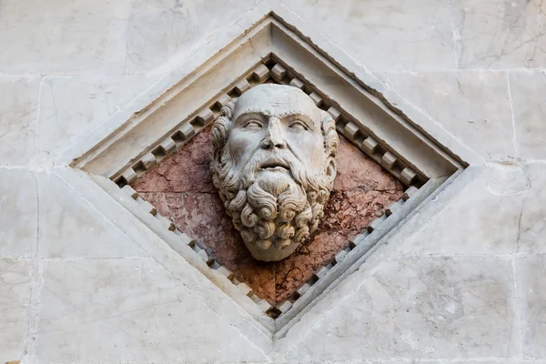 Głowy rzeźbione w marmur na fasadzie Baptysterium siena c — Zdjęcie stockowe