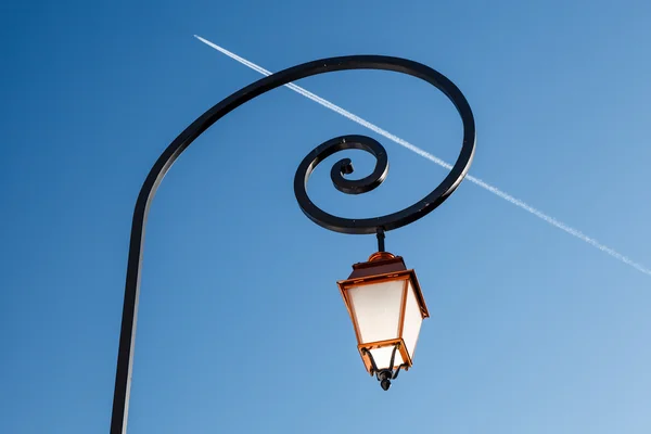 Stralende verlichte streetlamp en vliegtuig trail in achtergrond, meg — Stockfoto