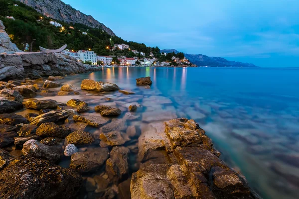 Rotsachtig strand en klein dorp in de buurt van omis in de avond, Dalmatië — Stockfoto