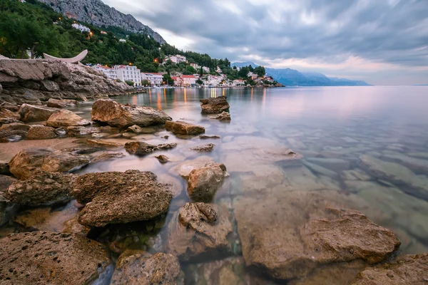 Playa rocosa y pequeño pueblo cerca de Omis en la mañana, Dalmacia —  Fotos de Stock