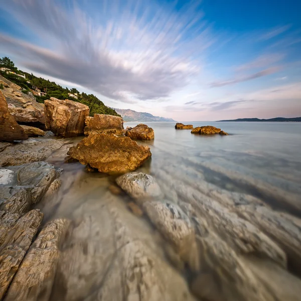 Rotsachtig strand en transparante Adriatische Zee in de buurt van omis in de evenin — Stockfoto