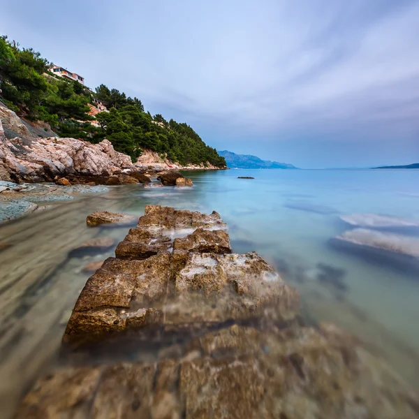 Sziklás strand és átlátszó Adriai-tenger közelében az estét omis — Stock Fotó