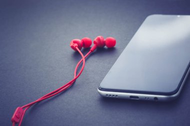 Cep telefonu ve kulaklık. Siyah ekranlı cep telefonu.
