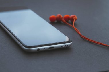 Cep telefonu ve kulaklık. Siyah ekranlı cep telefonu.