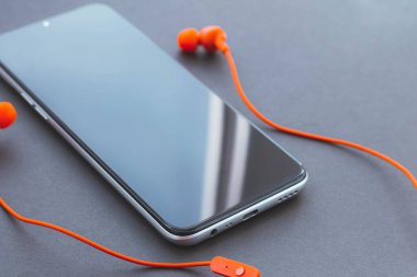 Cep telefonu ve kulaklık. Siyah ekranlı cep telefonu.