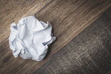 Masaya buruşmuş ve yırtılmış kağıt. Defterin bir parçası parçalanmış. Kağıt çöpü. Bir sepet dolusu not. Buruşmuş kağıt zemin üzerinde not defteri ve kalem.
