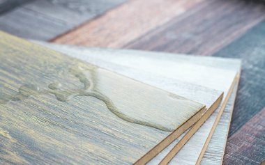 Laminat ve su. Su geçirmez kaplama. Ahşap zemin nemden etkilenmez. Zemin kaplamaları sudan korur. Yerde bir su birikintisi.